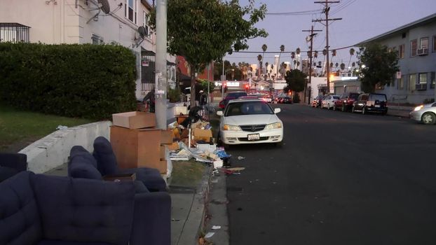 LOS ANGELES, CALIFORNIA, USA - 30 OCT 2019: Stack of waste on street roadside. Junk problem and recycling issues, pile of trash and garbage on sidewalk. Heap of mess, rubbish in metropolis downtown.
