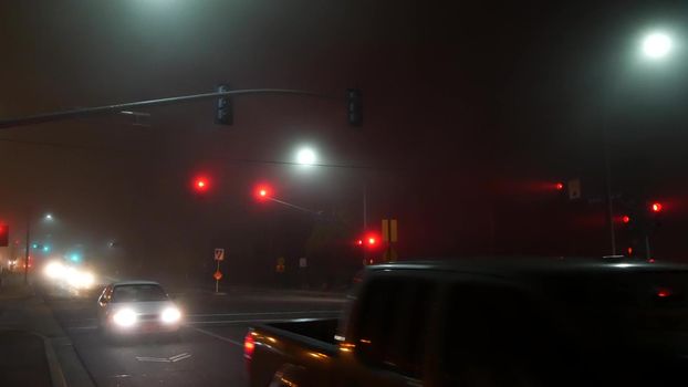 VISTA, CALIFORNIA USA - 24 JAN 2020: Marine layer, dense fog on driveway crossroad at night. June gloom, misty nebulous bad weather. Dangerous low visibility on road intersection. Car traffic safety.