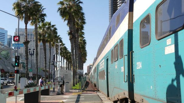 SAN DIEGO, CALIFORNIA USA - 13 FEB 2020: Coaster Commuter and palms, public rail transportation in America. Express passenger railway train, railroad nctd transport near Santa Fe station and Gaslamp.