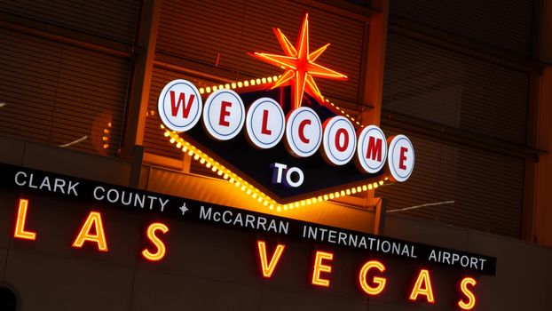 LAS VEGAS, NEVADA USA - 9 MAR 2020: Welcome to fabulous Sin City illuminated retro neon sign inside McCarran airport. Iconic greeting vintage styled signboard glowing. Gambling casino resort symbol.