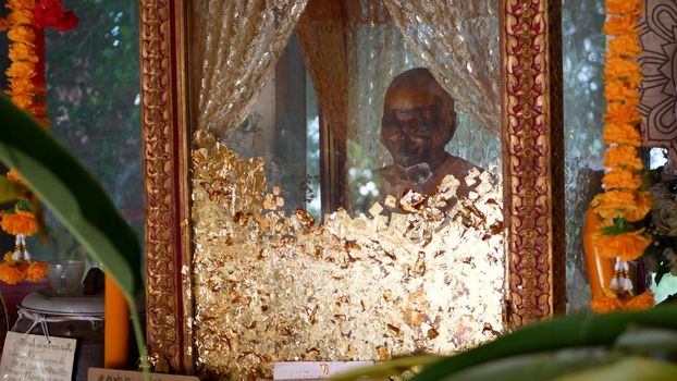 KOH SAMUI ISLAND, THAILAND - 17 JULY 2019: Wat Khiri Wongkaram Buddhist Temple. The mummified body of monk and gold leaf. Exotic tradition of storing the relics of saints who died during meditation