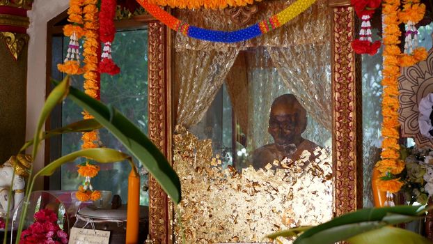 KOH SAMUI ISLAND, THAILAND - 17 JULY 2019: Wat Khiri Wongkaram Buddhist Temple. The mummified body of monk and gold leaf. Exotic tradition of storing the relics of saints who died during meditation