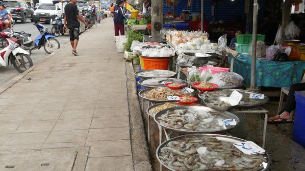 KOH SAMUI ISLAND, THAILAND - 10 JULY 2019: Food market for locals. Lively ranks with groceries. Typical daily life on the street in Asia. People go shopping for fruits vegetables, seafood and meat