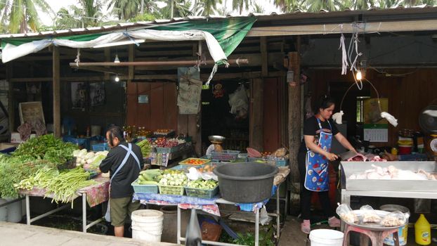 KOH SAMUI ISLAND, THAILAND - 10 JULY 2019: Food market for locals. Lively ranks with groceries. Typical daily life on the street in Asia. People go shopping for fruits vegetables, seafood and meat