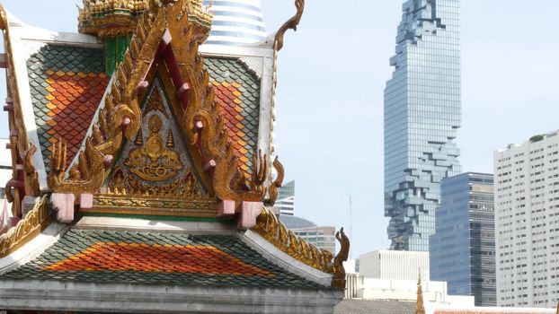 BANGKOK, THAILAND - 13 JULY, 2019: Conceptual contrast of oriental old traditional ancient temple and modern new futuristic Mahanakhon skyscraper. Classic buddhist wat compared to urban cityscape