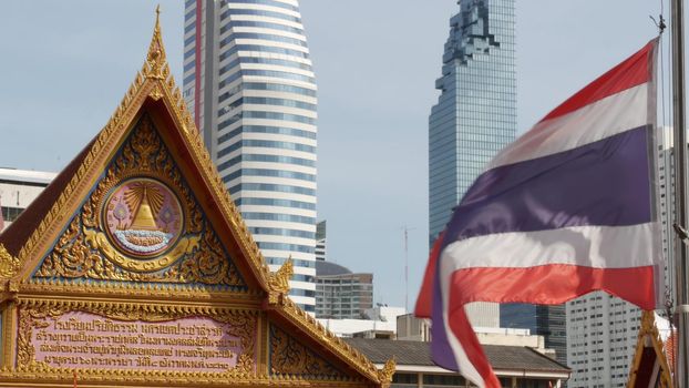 BANGKOK, THAILAND - 13 JULY, 2019: Conceptual contrast of oriental old traditional ancient temple and modern new futuristic Mahanakhon skyscraper. Classic buddhist wat compared to urban cityscape