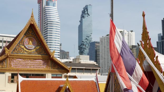 BANGKOK, THAILAND - 13 JULY, 2019: Conceptual contrast of oriental old traditional ancient temple and modern new futuristic Mahanakhon skyscraper. Classic buddhist wat compared to urban cityscape