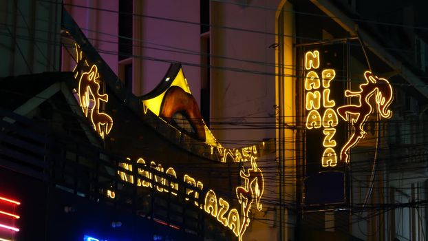 BANGKOK, THAILAND,13 JULY 2019 Vivid neon signs glowing, Nana Plaza street. Nightlife in erotic Red light district soi. Illuminated bar and adult go-go show club. Night life tourist entertainment