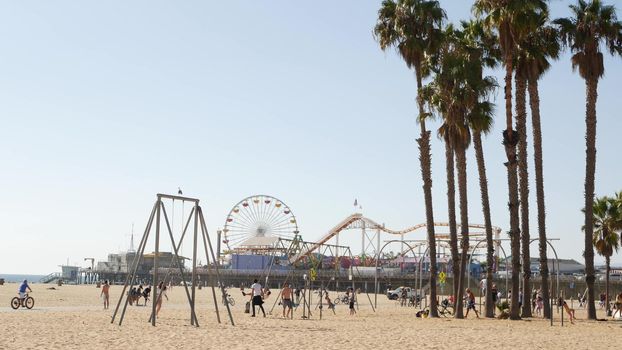 SANTA MONICA, LOS ANGELES CA USA - 28 OCT 2019: California summertime pacific ocean beach aesthetic, young people training and having fun on sports ground. Muscle beach and amusement park on pier.