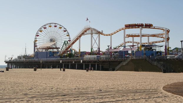 SANTA MONICA, LOS ANGELES CA USA - 28 OCT 2019: Famous classic california summertime symbol, pacific ocean beach resort. Iconic colorful retro ferris wheel and roller coaster, amusement park on pier.