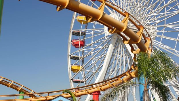 SANTA MONICA, LOS ANGELES, USA - 28 OCT 2019: Iconic colorful retro ferris wheel, roller coaster in amusement park. Famous classic california summertime symbol, pier of pacific ocean beach resort.