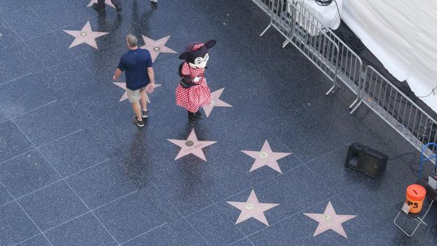 LOS ANGELES, CALIFORNIA, USA - 7 NOV 2019: Walk of fame promenade on Hollywood boulevard in LA. Pedastrians walking near celebrity stars on asphalt. Walkway floor near Dolby and TCL Chinese Theatre.