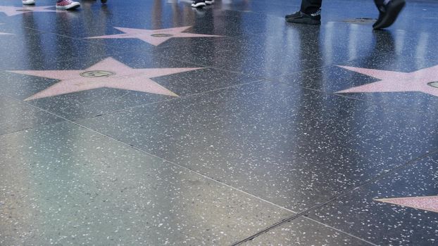 LOS ANGELES, CALIFORNIA, USA - 7 NOV 2019: Walk of fame promenade on Hollywood boulevard in LA. Pedastrians walking near celebrity stars on asphalt. Walkway floor near Dolby and TCL Chinese Theatre.