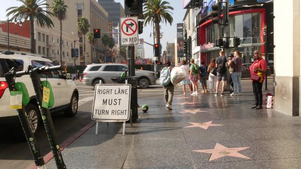 LOS ANGELES, CALIFORNIA, USA - 7 NOV 2019: Walk of fame promenade, Hollywood boulevard in LA city. Pedastrians walking on sidewalk of street. Entertainment and cinema industry iconic tourist landmark.