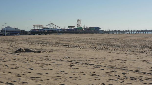 SANTA MONICA, LOS ANGELES CA USA - 19 DEC 2019: Alone anonymous man looks like unemployed and homeless sleeping on beach sand. Homelessness and begging crisis, social issue, poor people live on street