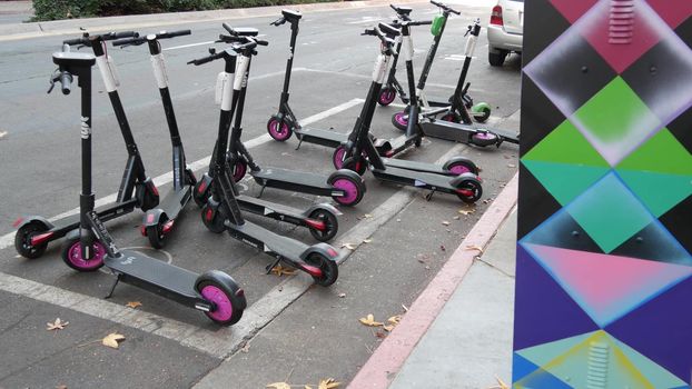 SAN DIEGO, CALIFORNIA USA - 4 JAN 2020: Row of ride sharing electric scooters parked on street in Gaslamp Quarter. Rental dockless public bikes, eco transport in city. Rent kick cycle with mobile app.