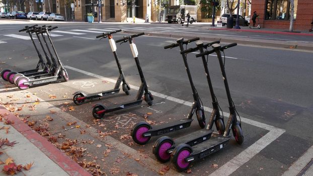 SAN DIEGO, CALIFORNIA USA - 4 JAN 2020: Row of ride sharing electric scooters parked on street in Gaslamp Quarter. Rental dockless public bikes, eco transport in city. Rent kick cycle with mobile app.