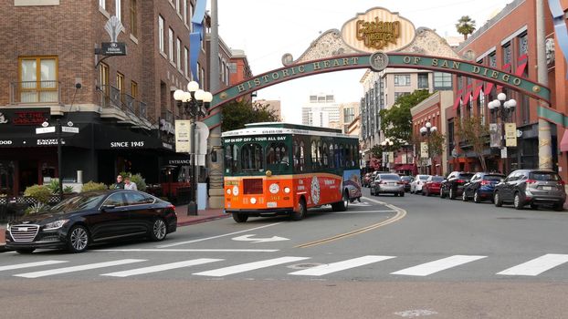 SAN DIEGO, CALIFORNIA USA - 30 JAN 2020: Gaslamp Quarter historic entrance arch sign on 5th avenue. Orange iconic retro trolley, hop-on hop-off bus and tourist landmark, Old Town Sightseeing Tour.