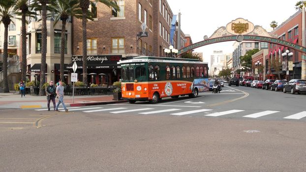 SAN DIEGO, CALIFORNIA USA - 30 JAN 2020: Gaslamp Quarter historic entrance arch sign on 5th avenue. Orange iconic retro trolley, hop-on hop-off bus and tourist landmark, Old Town Sightseeing Tour.