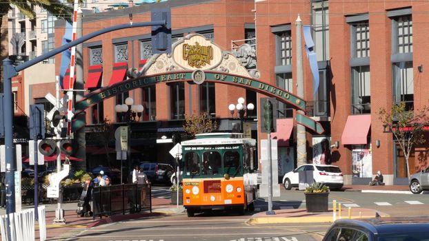 SAN DIEGO, CALIFORNIA USA - 13 FEB 2020: Gaslamp Quarter historic entrance arch sign on 5th avenue. Orange iconic retro trolley, hop-on hop-off bus and tourist landmark, Old Town Sightseeing Tour.
