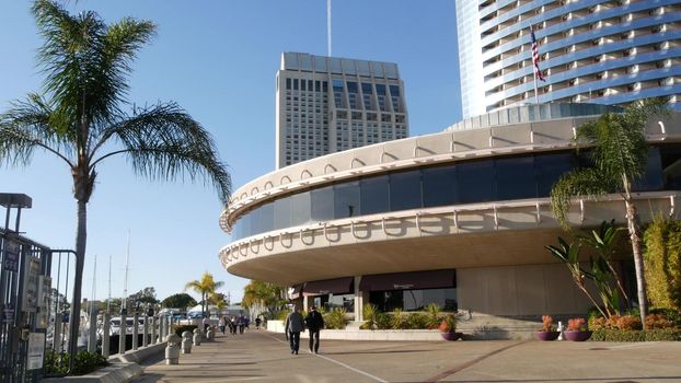 SAN DIEGO, CALIFORNIA USA - 13 FEB 2020: Pedestrians and highrise buildings in city downtown. Street life of american metropolis. Urban street and citizens walking on walkway. Embarcadero marina park.