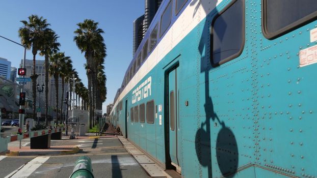 SAN DIEGO, CALIFORNIA USA - 13 FEB 2020: Coaster Commuter and palms, public rail transportation in America. Express passenger railway train, railroad nctd transport near Santa Fe station and Gaslamp.