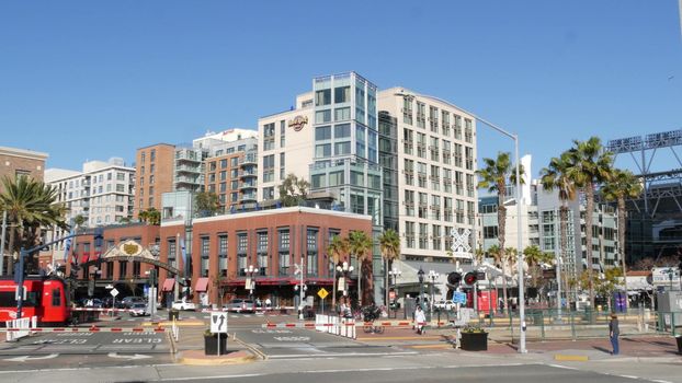 SAN DIEGO, CALIFORNIA USA - 13 FEB 2020: Gaslamp Quarter entrance arch sign. Red MTS trolley on level crossing. American public passenger rail transport. Tram and retro signboard on road intersection.