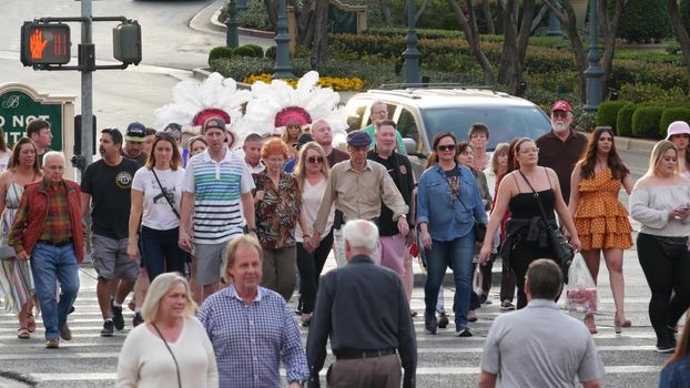 LAS VEGAS, NEVADA USA - 5 MAR 2020: People on pedestrian walkway. Multicultural men and women walking on city promenade. Crowd of citizens on sidewalk. Diversity of multiracial faces in metropolis.