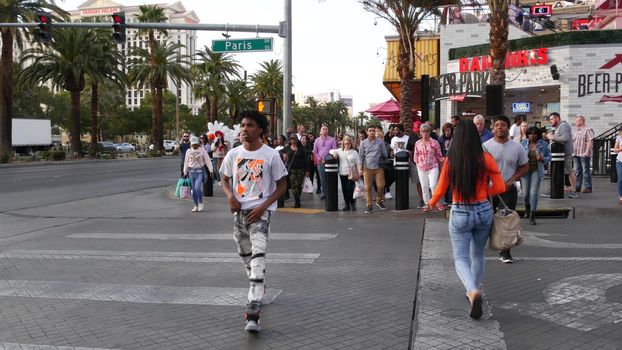 LAS VEGAS, NEVADA USA - 5 MAR 2020: People on pedestrian walkway. Multicultural men and women walking on city promenade. Crowd of citizens on sidewalk. Diversity of multiracial faces in metropolis.