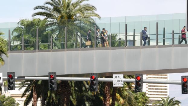 LAS VEGAS, NEVADA USA - 7 MAR 2020: People on pedestrian skyway. Multicultural men and women walk on skybridge. Crowd of citizens on pedway. Diversity of multiracial tourists on skywalk in metropolis.
