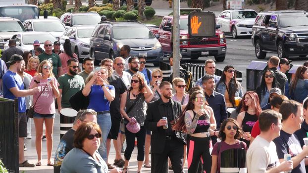 LAS VEGAS, NEVADA USA - 7 MAR 2020: People on pedestrian walkway. Multicultural men and women walking on city promenade. Crowd of citizens on sidewalk. Diversity of multiracial faces in metropolis.