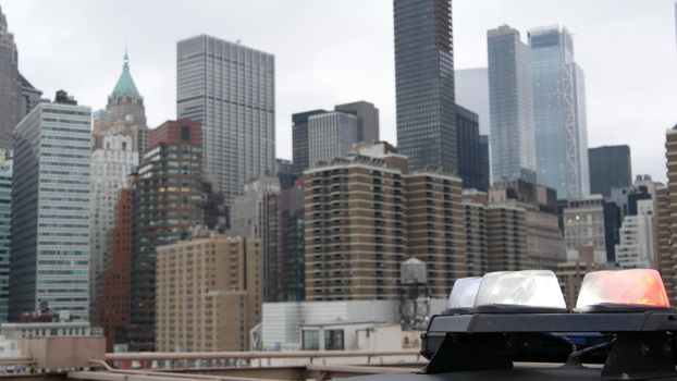 NEW YORK CITY, USA - 12 MAR 2020: Emergency siren glowing, 991 police patrol car on Brooklyn bridge. NYPD auto, symbol of crime prevention and safety in Manhattan. Metropolis security and protection.
