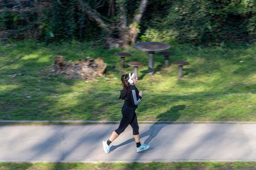 terni,italy february 20 2021:panning of woman running in park with headphones