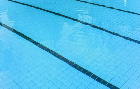 Calm water on empty swimming pool, dark lanes marks visible floor.