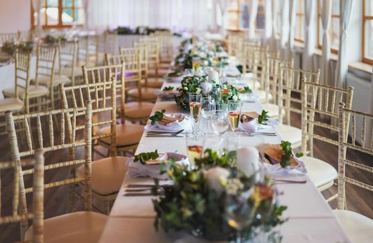 Tables with decoration and plates ready at wedding reception, shallow depth of field photo.