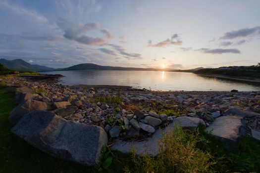 A rocky boulder sea shore at sunset. Looking west near East Suisnish on the Isle of Raasay, isle of skye in the distance. A fish eye perspective.