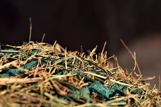 Close-up of hay under a green hay against a blurred background