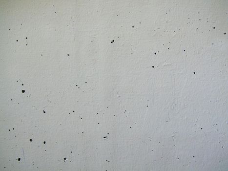 Close-up of a painted white concrete wall with holes in the surface.Texture or background