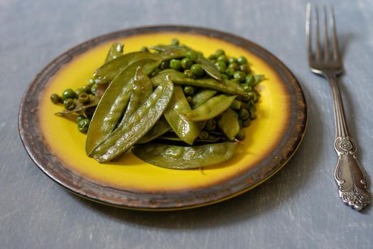 Fried green peas on a ceramic yellow plate