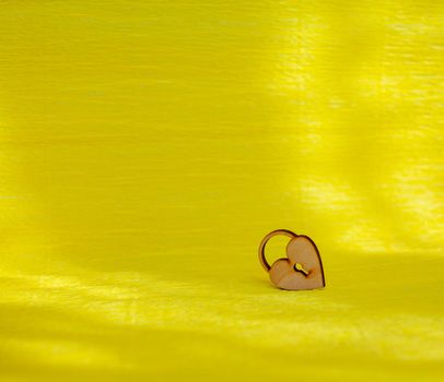 A wooden heart with a keyhole on a yellow background. There is a place for the text.