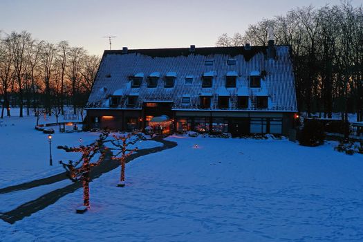 Traditional snowy farm house in winter in the countryside from the Netherlands at sunset