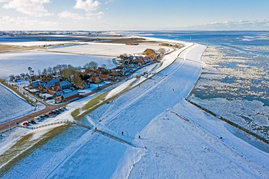 Aerial from snowy village Moddergat in Friesland at a frozen Waddensea in the Netherlands in winter