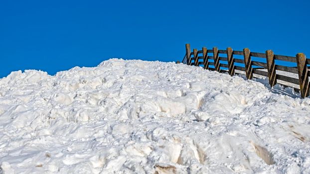 Fence, lots of snow and a blue sky