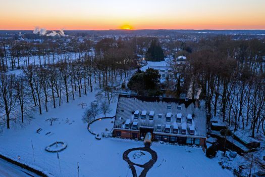 Aerial from a traditional dutch landscape in winter at sunset in the Netherlands