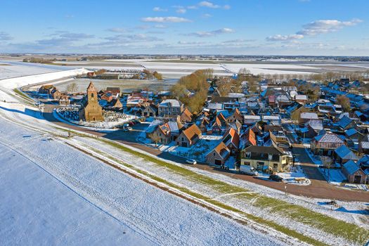 Aerial from snowy village Wierum in Friesland at a frozen Waddensea in the Netherlands in winter