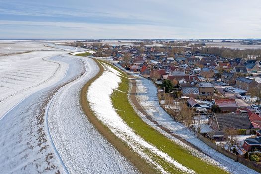 Aerial from snowy village Moddergat in Friesland at a frozen Waddensea in the Netherlands in winter