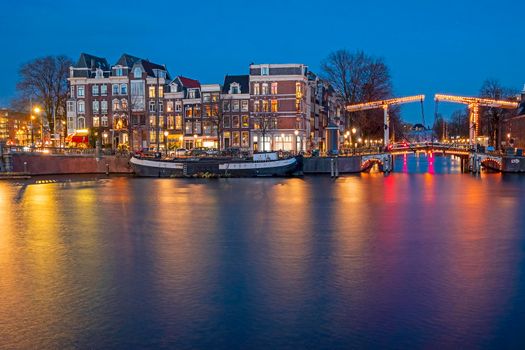 City scenic from Amsterdam by night at the river Amstel in the Netherlands