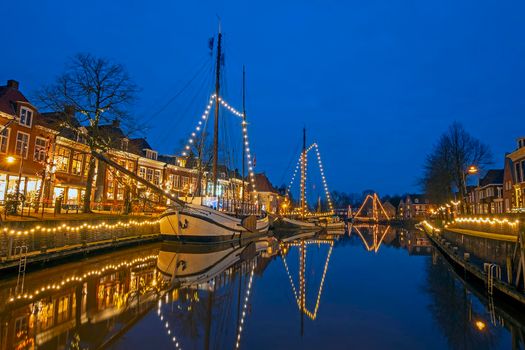 Decorated traditional boats in the harbor from Dokkum in the Netherlands at christmas at sunset