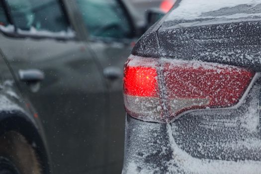 frozen car tail light with snow at winter evening with blurry background