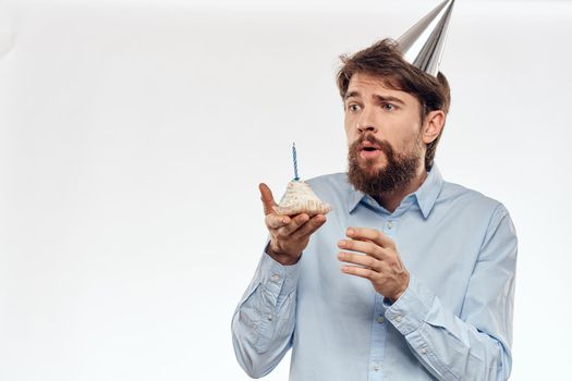 A man celebrate a birthday on a light background with a cake in a plate flute fun